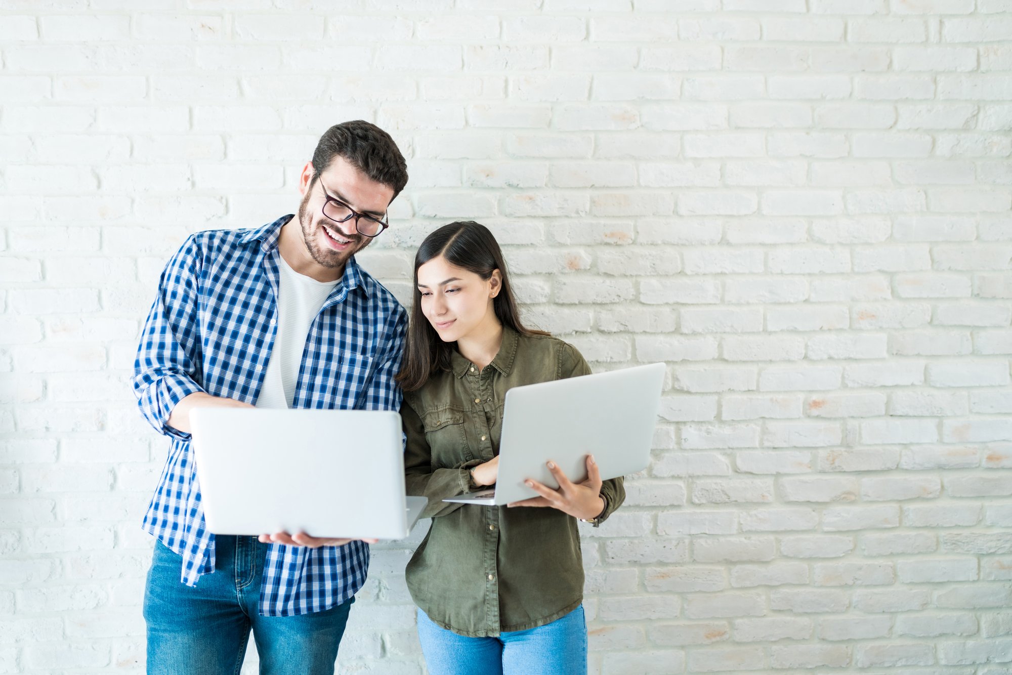 professional-business-partners-working-laptops-while-standing-against-white-wall-workplace professional-business-partners-working-laptops-while-standing-against-white-wall-workplace